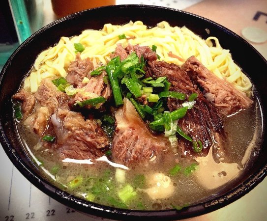 A bowl of Hong Kong beef brisket noodles with egg noodles, tender brisket and spring onion