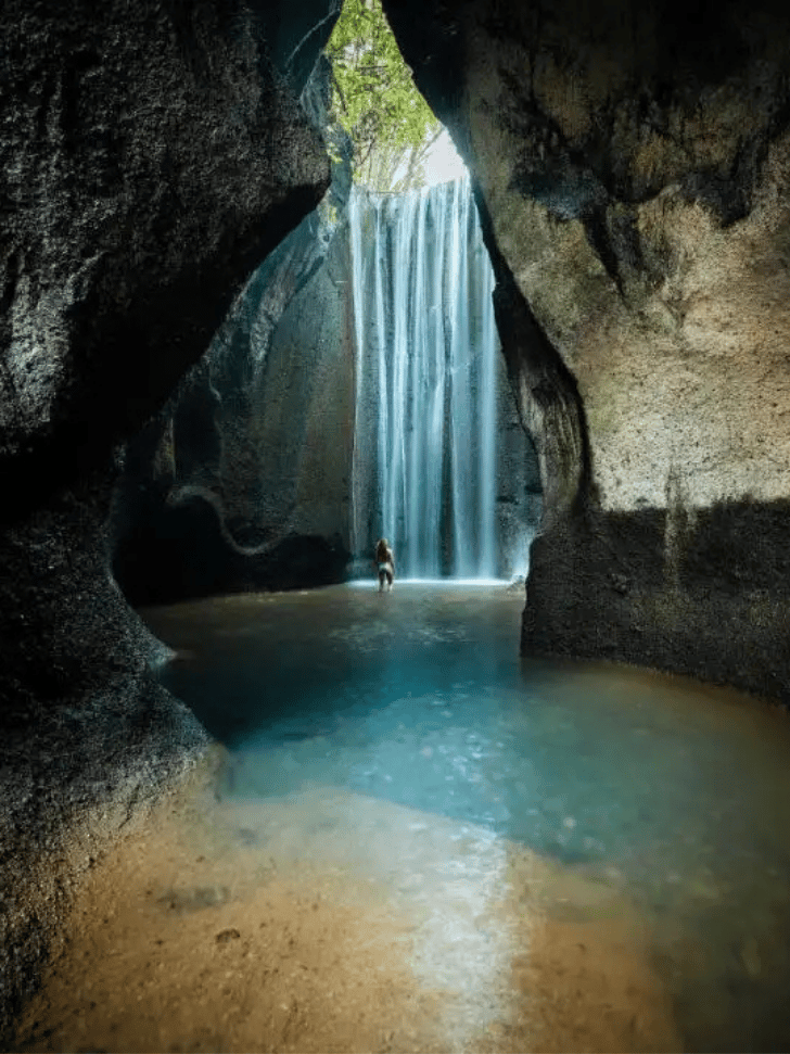 Sunbeam falling through a slot canyon onto Tukad Cepung cave waterfall, Bali