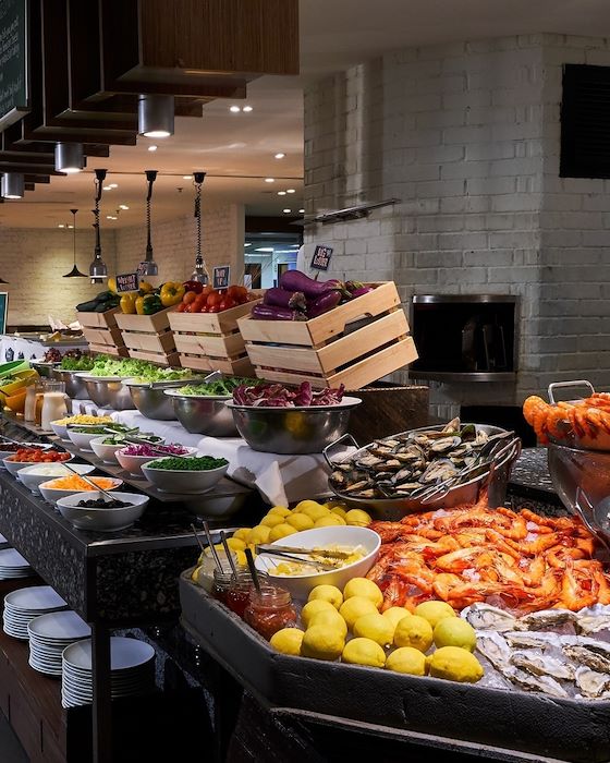 Hotel breakfast buffet with fresh seafood on ice, salad bowls and crates of produce