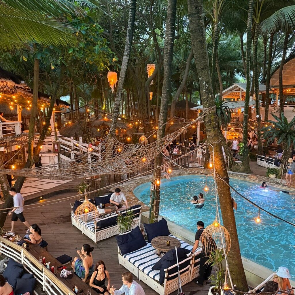 Boho beach club with a pool, string lights and palms at dusk in Canggu