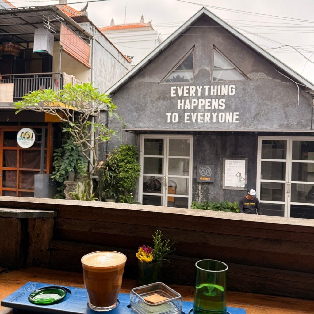 A latte on a wooden ledge overlooking a cafe courtyard in Bali