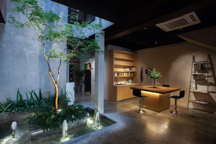 Atelier Hotel's industrial-style lounge with an indoor tree, water feature and bar seating