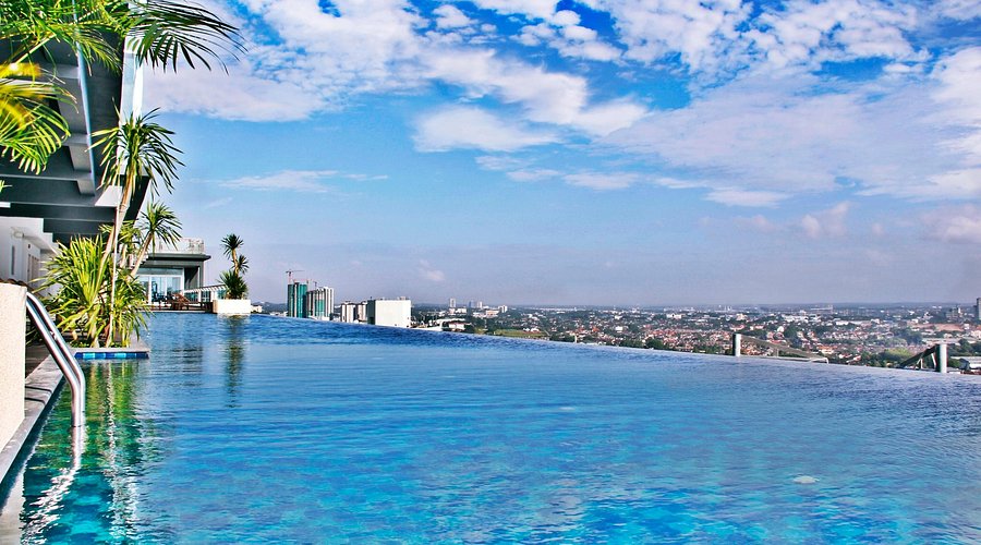 Holiday Villa's rooftop infinity pool with palms overlooking the Johor Bahru skyline