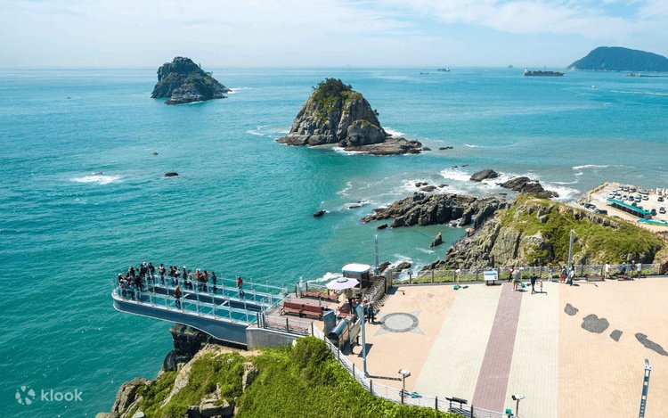 Visitors on the Oryukdo Skywalk glass deck above the sea, islets beyond