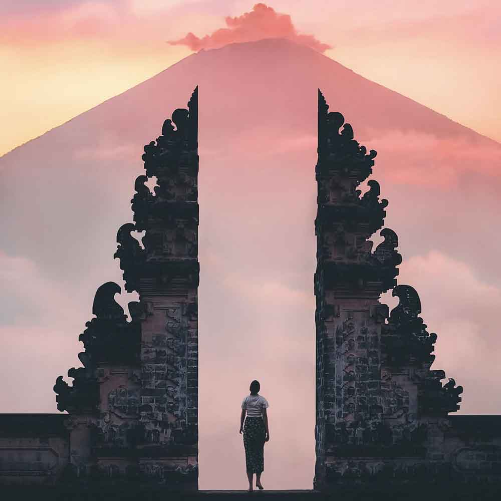 Person framed between the split gates of Lempuyang temple with Mount Agung behind