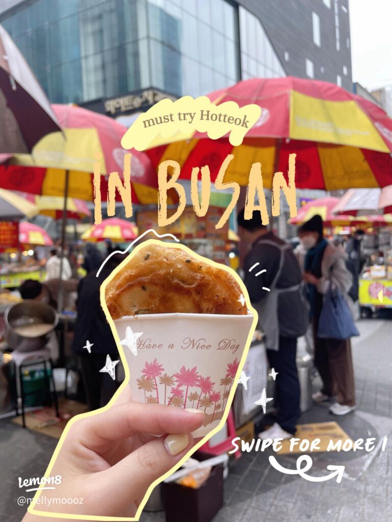 Hand holding a seed-stuffed ssiat hotteok pancake at a Busan street market