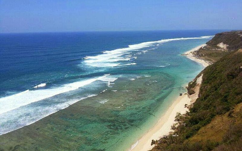 Long white-sand beach and reef stretching below cliffs in south Bali