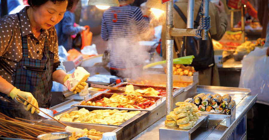 Street-food vendor grilling skewers and snacks at a night stall in Nampo