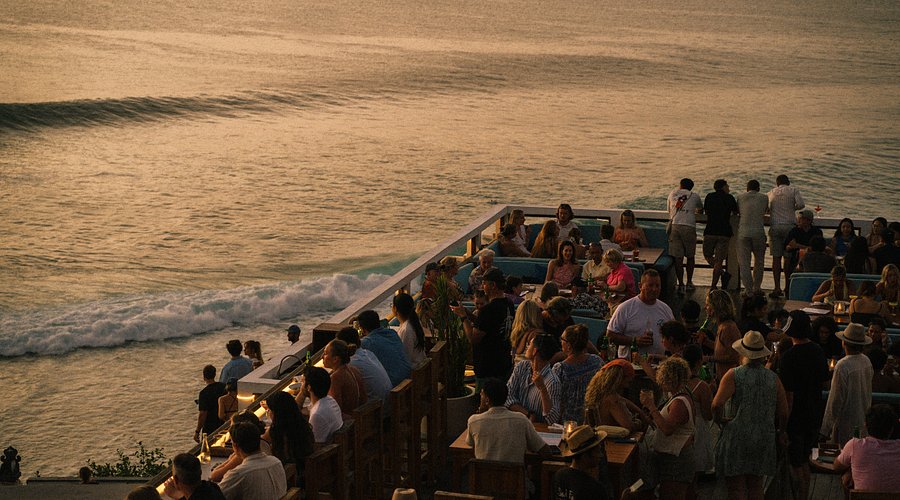 Crowd at a clifftop bar overlooking the Uluwatu surf break at sunset
