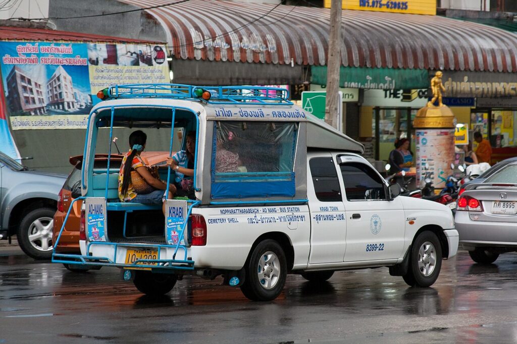 A blue songthaew shared pickup taxi with passengers on a Krabi Town street