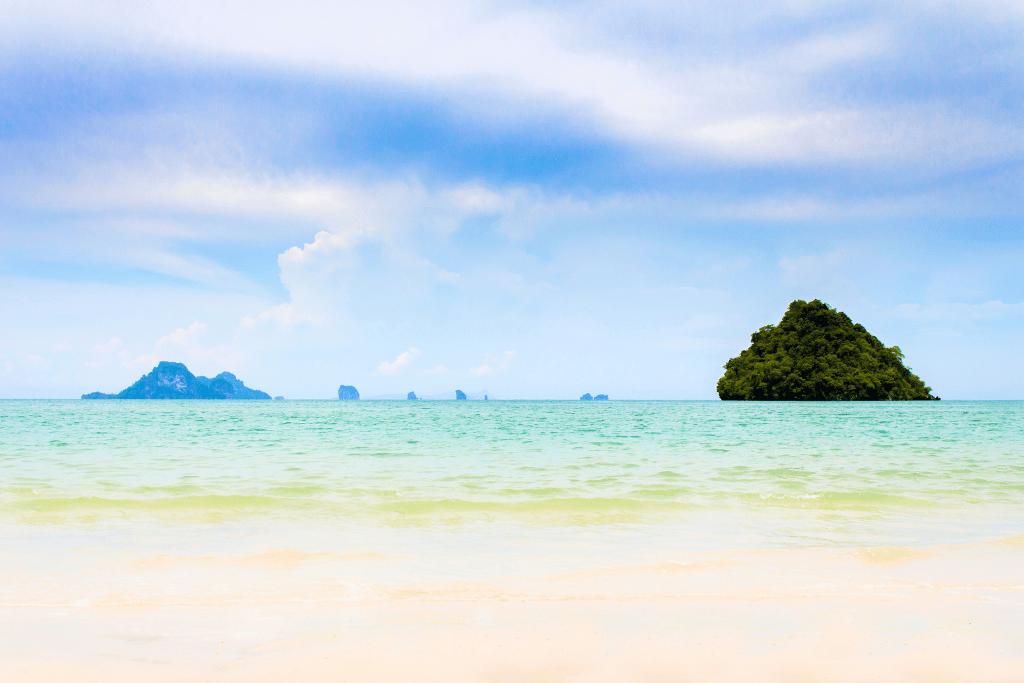 Calm shallow beach with small limestone islands on the horizon at Nopparat Thara, Krabi
