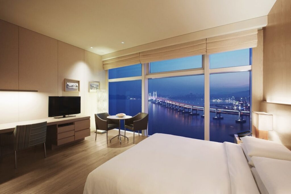 Park Hyatt Busan hotel room with floor-to-ceiling windows overlooking Busan's Gwangan Bridge at dusk