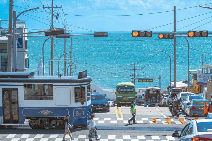 Traffic and a tram at a seaside road crossing overlooking the ocean in Busan