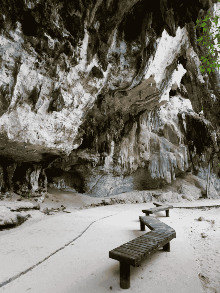 Limestone cave with stalactites and wooden benches on the sand at Railay, Krabi