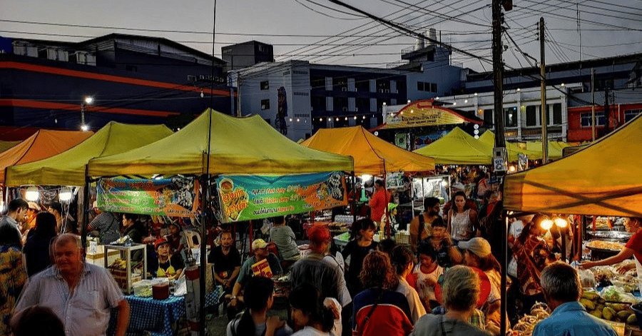 Crowds and lit food stalls under yellow tents at a Krabi Town night market