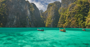 Longtail boats on turquoise water between towering limestone cliffs in Krabi