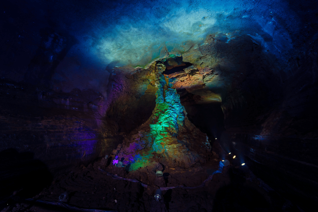 Colourfully lit lava column inside the dark Manjanggul Lava Tube cave, Jeju
