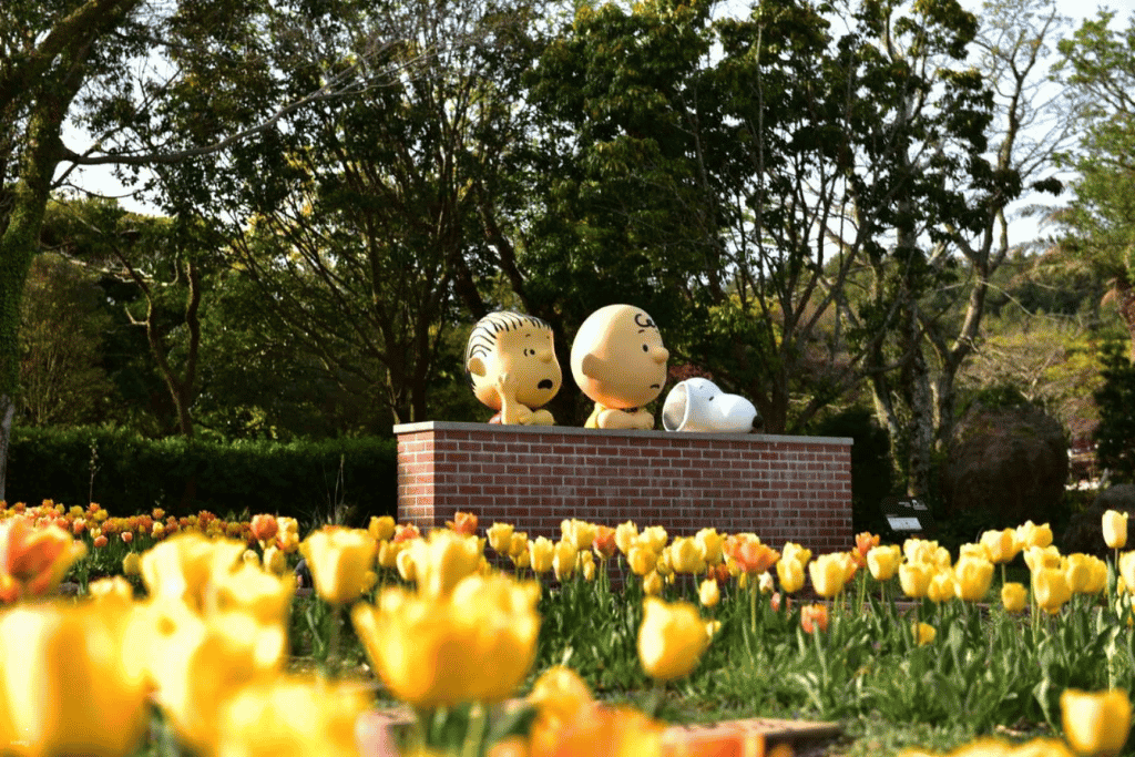Peanuts character statues among yellow tulips at Snoopy Garden, Jeju