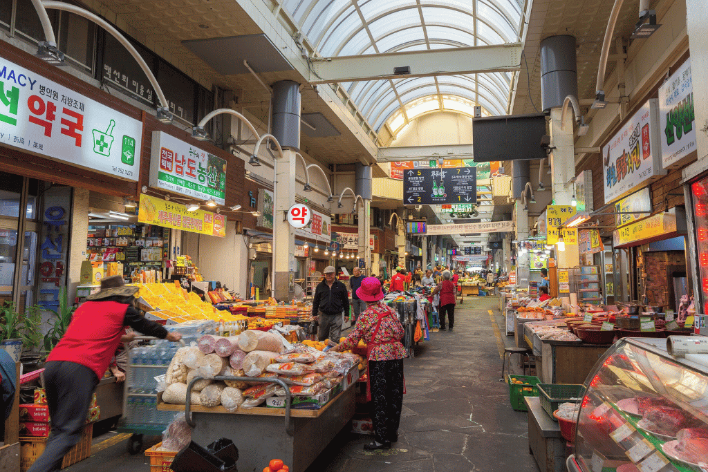 Shoppers browsing produce and food stalls in the covered Seogwipo Olle Market arcade