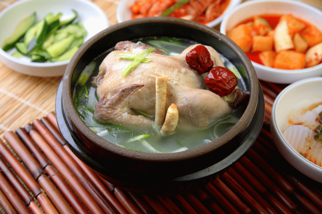 Whole-chicken ginseng soup in a stone pot with jujube and Korean side dishes