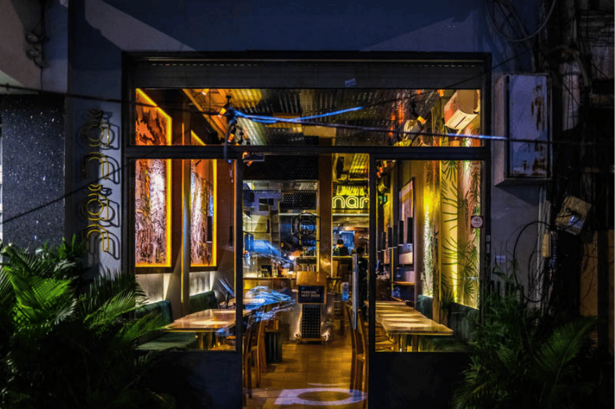 The warmly lit glass storefront of Anan Saigon restaurant at night