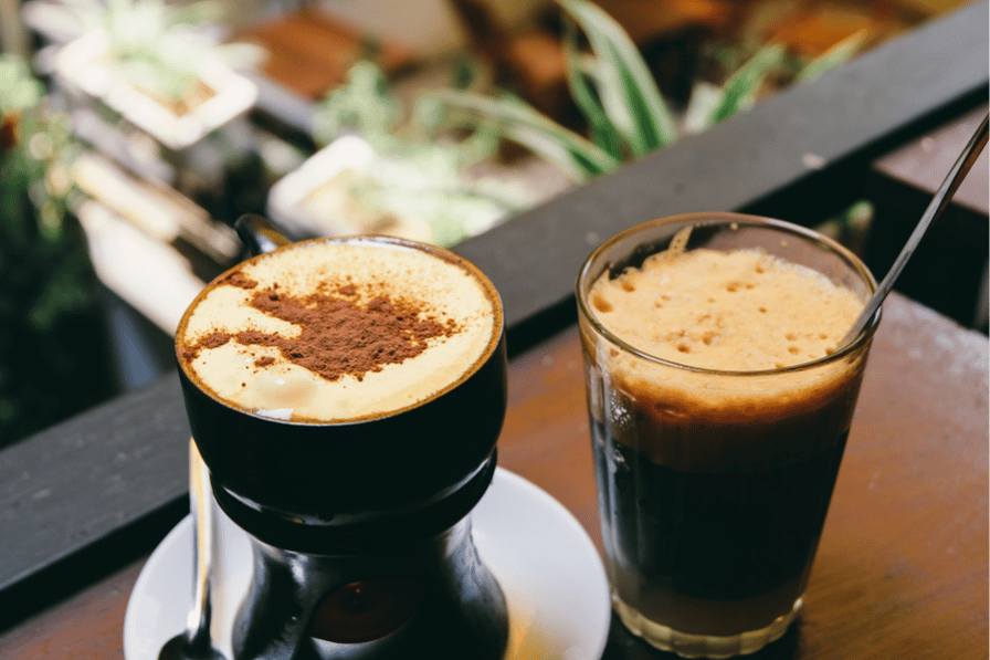 Two Vietnamese coffees on a table, one with a frothy egg-coffee top and one iced