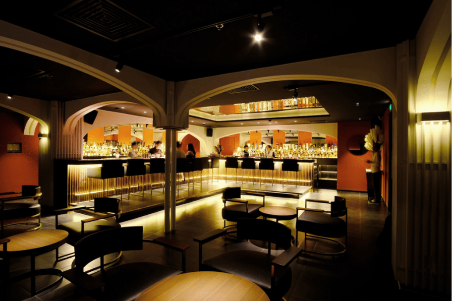 The dim, plush interior of a speakeasy-style cocktail bar with curved seating