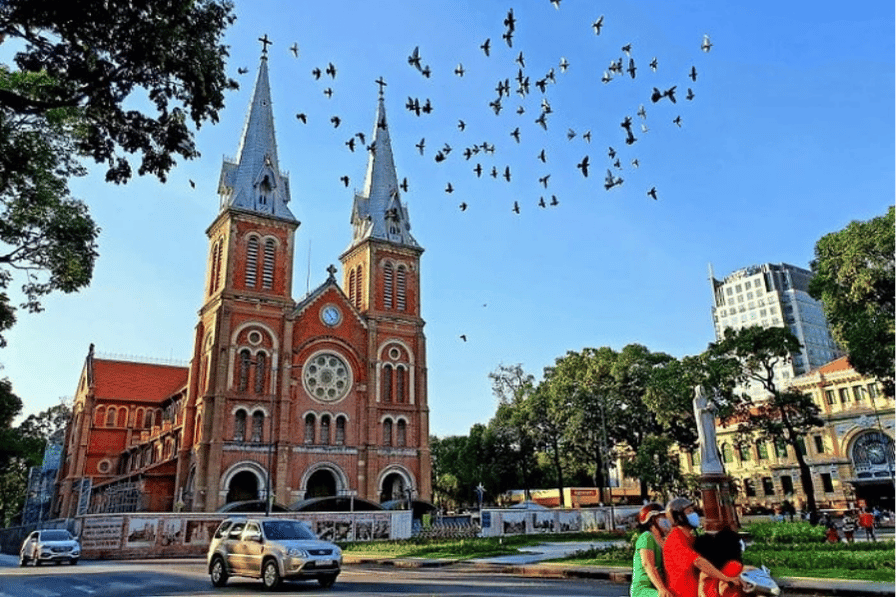 Red-brick Notre-Dame Cathedral of Saigon with birds in flight over the square