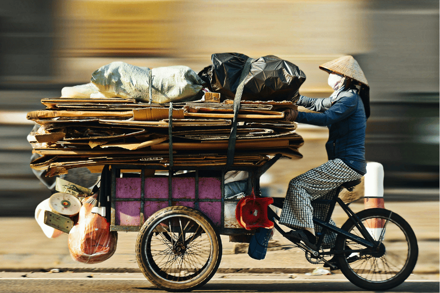 A cargo cyclist hauling goods through a Ho Chi Minh City street, motion-blurred
