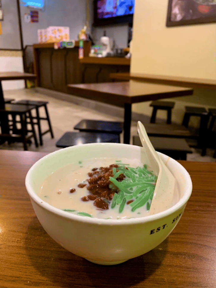 A bowl of chendol with green pandan jelly, red beans and coconut milk