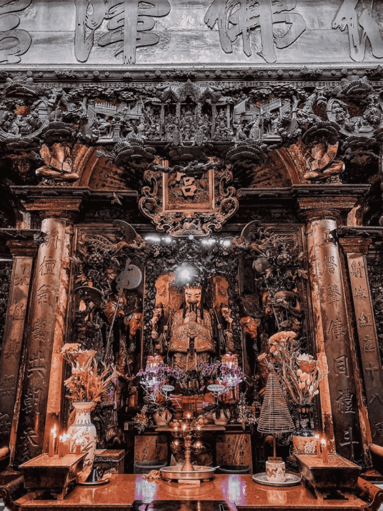 Ornate carved wooden altar and statues inside the incense-filled Jade Emperor Pagoda