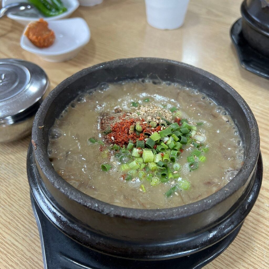 Stone bowl of Jeju haejangguk pork soup topped with spring onion and chilli at Ujin Haejangguk
