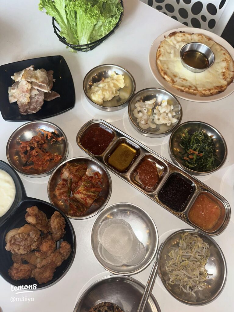 Korean barbecue side dishes, grilled pork and fried chicken laid out on a table