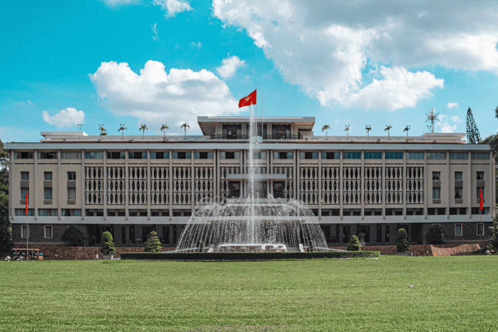 Independence Palace with its fountain and Vietnamese flag under a blue sky