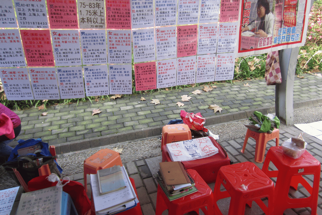 Walls of posted profiles and small red stools at Shanghai's weekend marriage market in People's Park