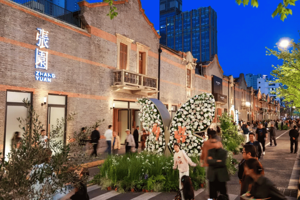 Restored brick shikumen buildings and a floral display lit at dusk in Shanghai's Zhang Yuan