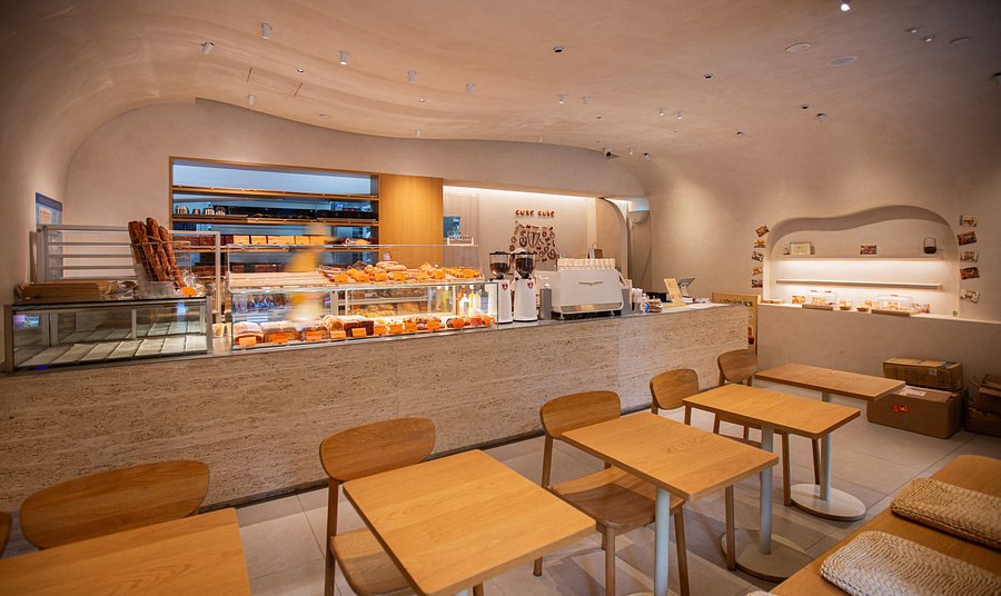 A modern cafe interior with curved walls, a pastry counter and wooden tables in Shanghai