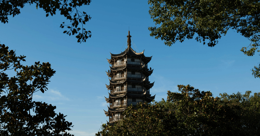 The tiered brick Longhua Pagoda rising above green trees against a blue sky in Shanghai