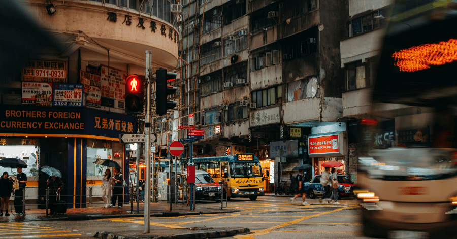 Busy Hong Kong street intersection at dusk with trams, buses and lit shop signs