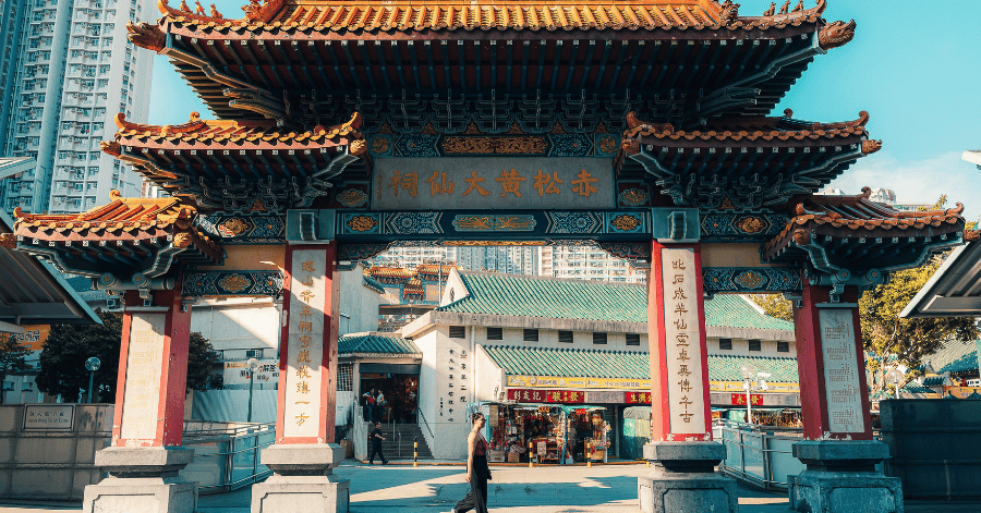 Ornate red-and-gold traditional Chinese temple gateway in Hong Kong under a blue sky