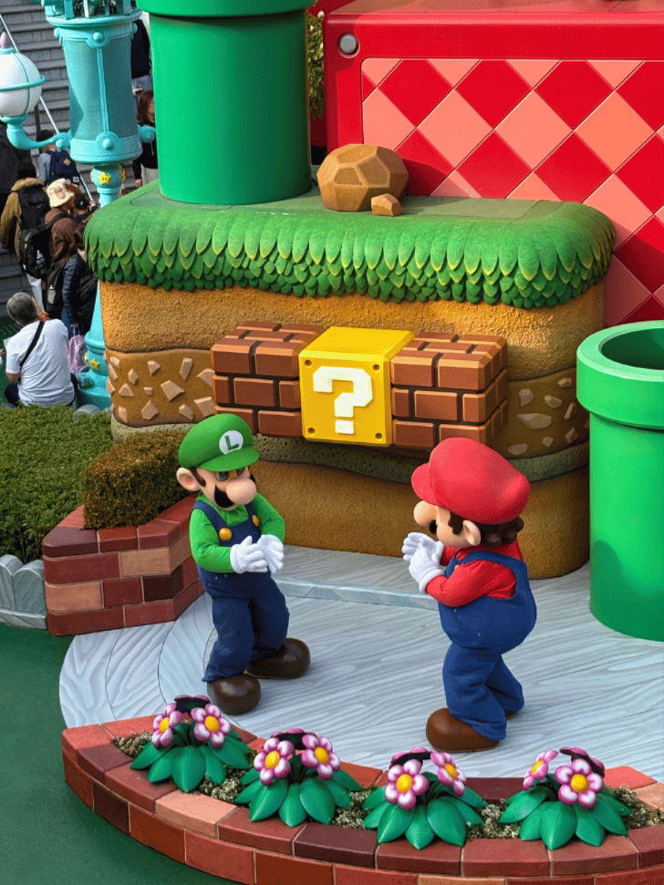 Mario and Luigi character models beside a question block and warp pipe in Super Nintendo World