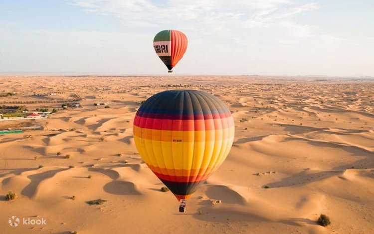 Two hot air balloons drifting over the rolling sand dunes of the Dubai desert