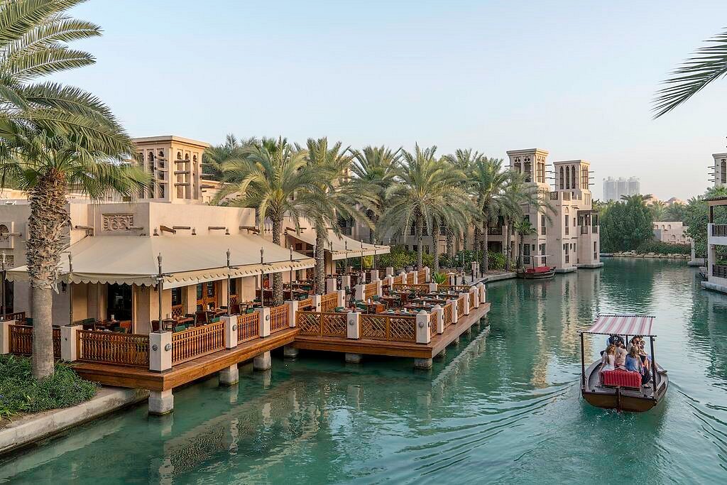 A traditional abra boat on the canal past waterside restaurants at Souk Madinat Jumeirah