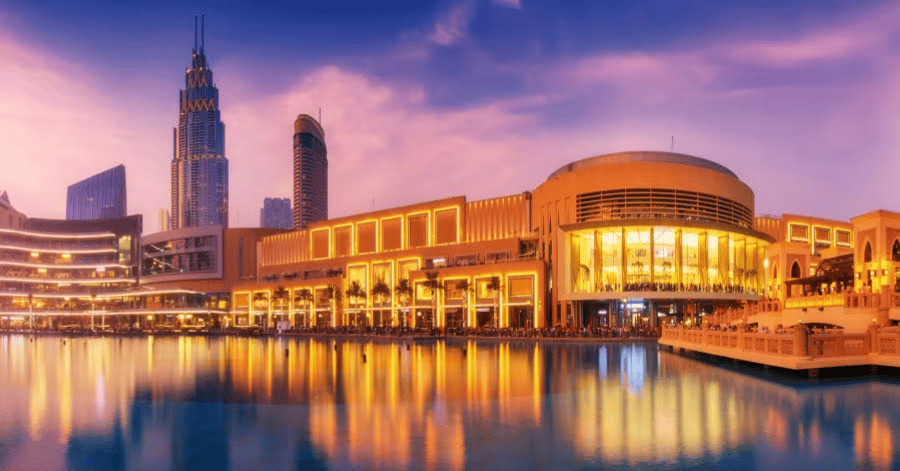 The Dubai Mall exterior lit at dusk beside the fountain lake and Downtown skyline