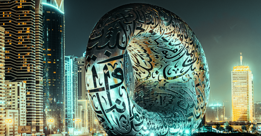 The torus-shaped Museum of the Future lit up at night with Arabic calligraphy on its facade