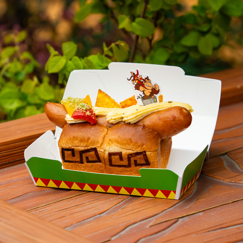 The DK Wild Hot Dog topped with avocado and cheese sauce in a Donkey Kong Country themed box