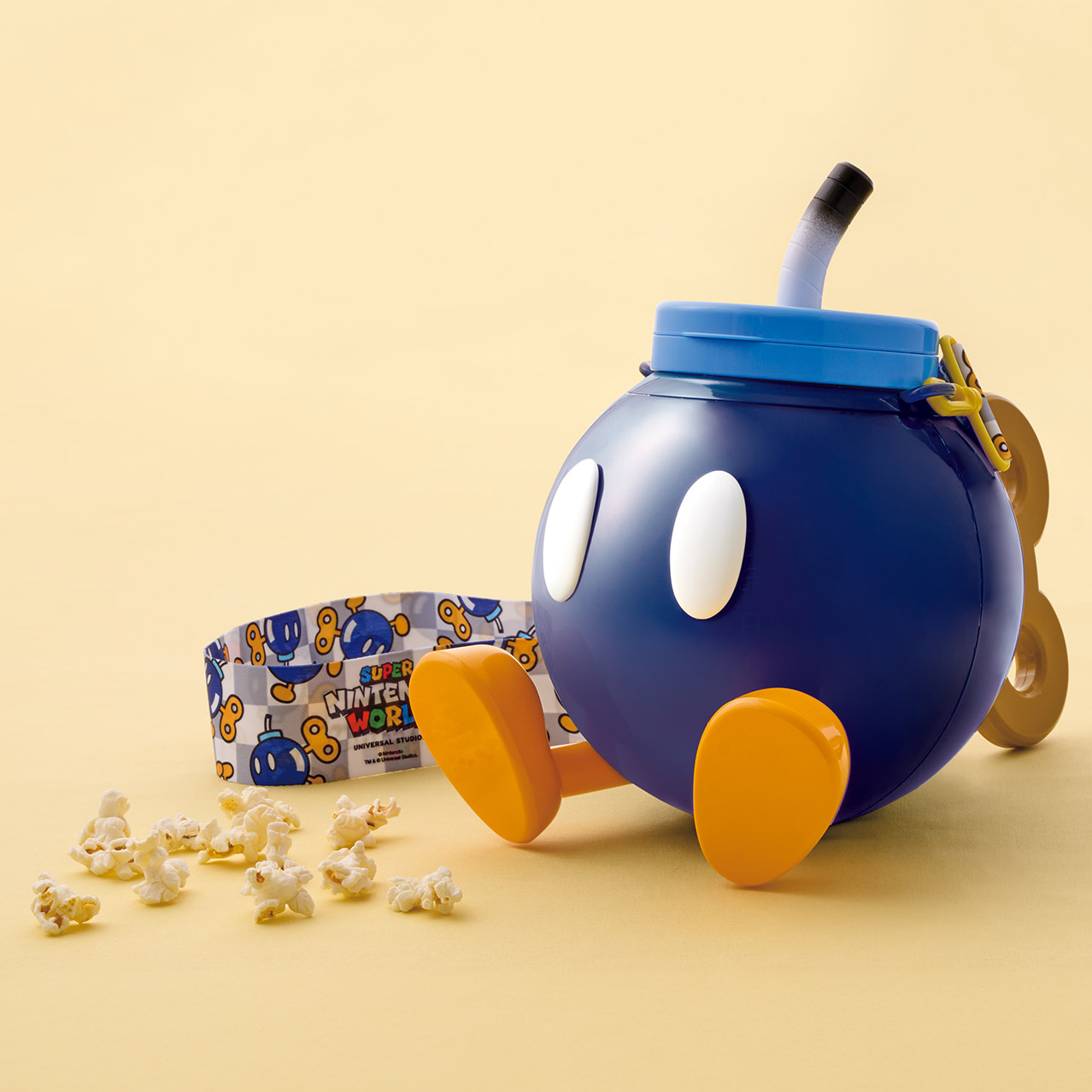 A Bob-omb-shaped souvenir popcorn bucket with popcorn scattered beside it