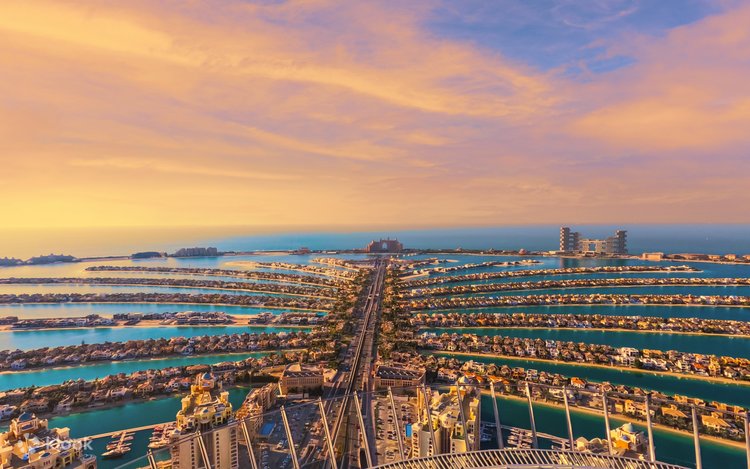 Aerial view of Palm Jumeirah's palm-shaped fronds stretching out towards Atlantis at sunset