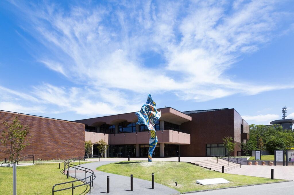 The brick facade of Fukuoka Art Museum with a colourful sculpture in the forecourt