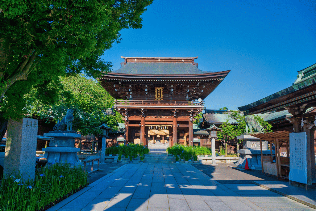 The wooden main gate of Miyajidake Shrine flanked by guardian lion-dog statues and stone lanterns